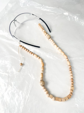 Handmade beaded glasses chain made from reprocessed wooden beads in natural, laid flat with eyewear