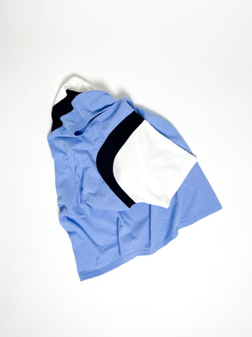 Upcycled panel T-shirt in baby blue, black and white, made from second-hand T-shirts and deadstock jersey. Flat lay on white background.