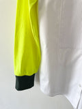 Detail of a Pleated white shirt with neon yellow T-shirt sleeve and khaki cuff on a white background 