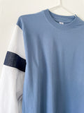 Detail of a Blue T-shirt with white shirt sleeves and denim stripes on a white background.
