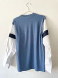Back of a Blue T-shirt with white shirt sleeves and denim stripes on a white background.