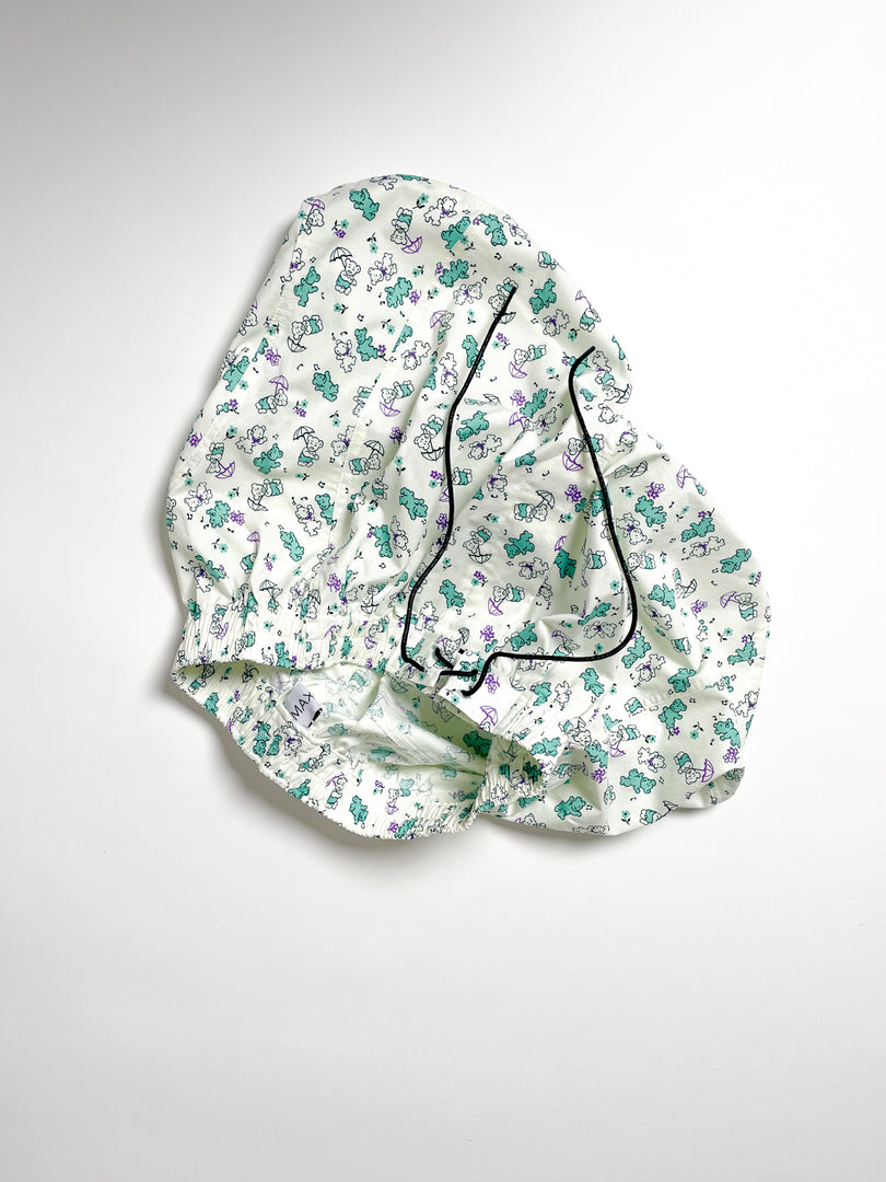Green and purple Teddy bear print cotton boxer shorts with a board shorts-inspired design, featuring an elastic waistband, white drawstring, and relaxed fit.